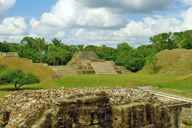 Ancient ruins with a pyramid-like structure surrounded by lush greenery.